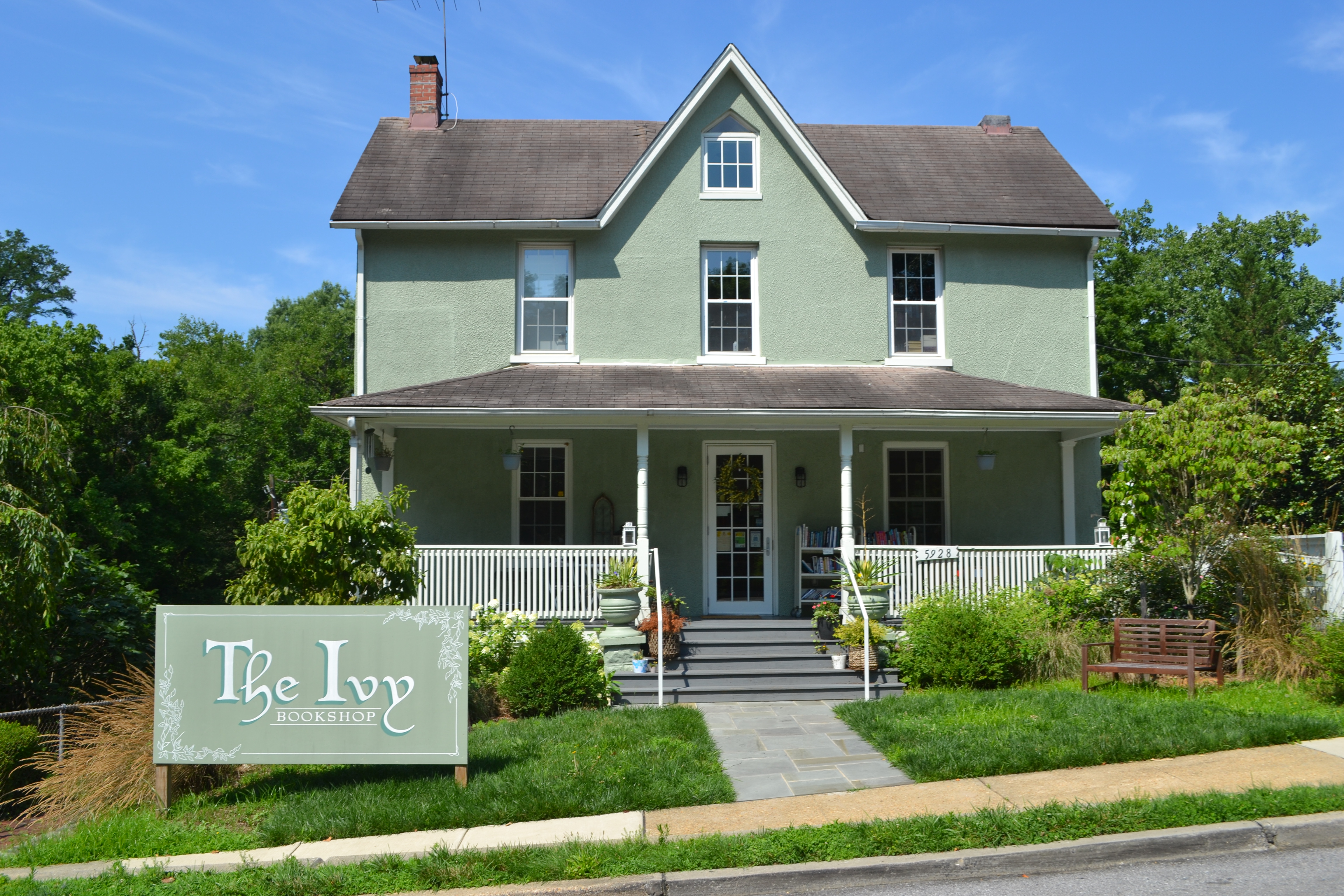 An outdoor photo of the exterior of The Ivy Bookstore, which is housed inside a green house with a white porch.