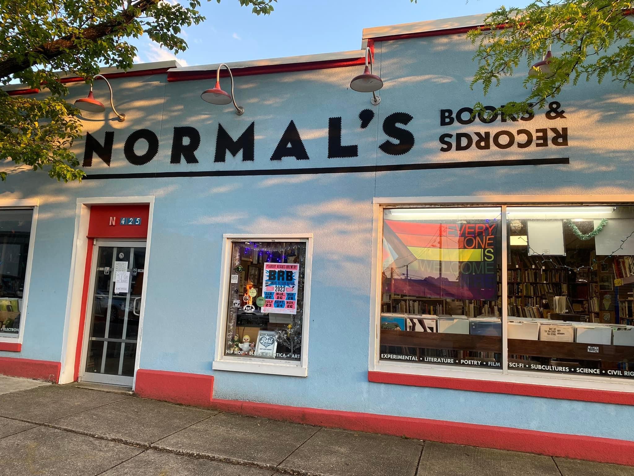 An exterior picture of Normal's Books & Records featuring a bright blue building with red trip and windows.