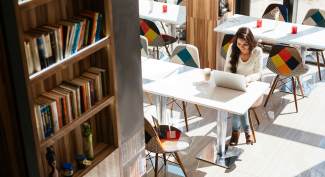 Woman working on her laptop in a sunny bookstore