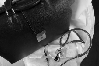 A medical doctor bag, stethoscope, and white doctor's coat