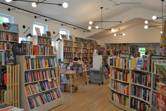 An interior picture of Ivy Bookshop featuring bookshelves, wood floors, and modern lights.