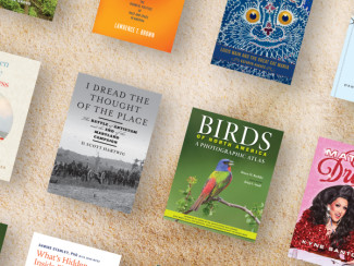 Various books by Hopkins Press on a sandy background.