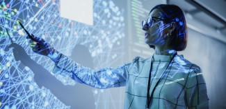 Teacher standing in front of white board with digital projection on it. 