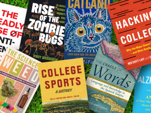 A variety of books from Hopkins Press laying in green grass.